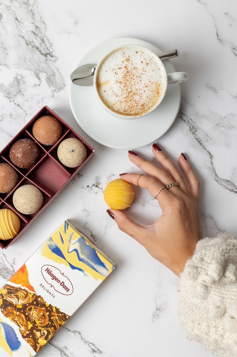 Hand holding Haagen Dazs Delights next to box