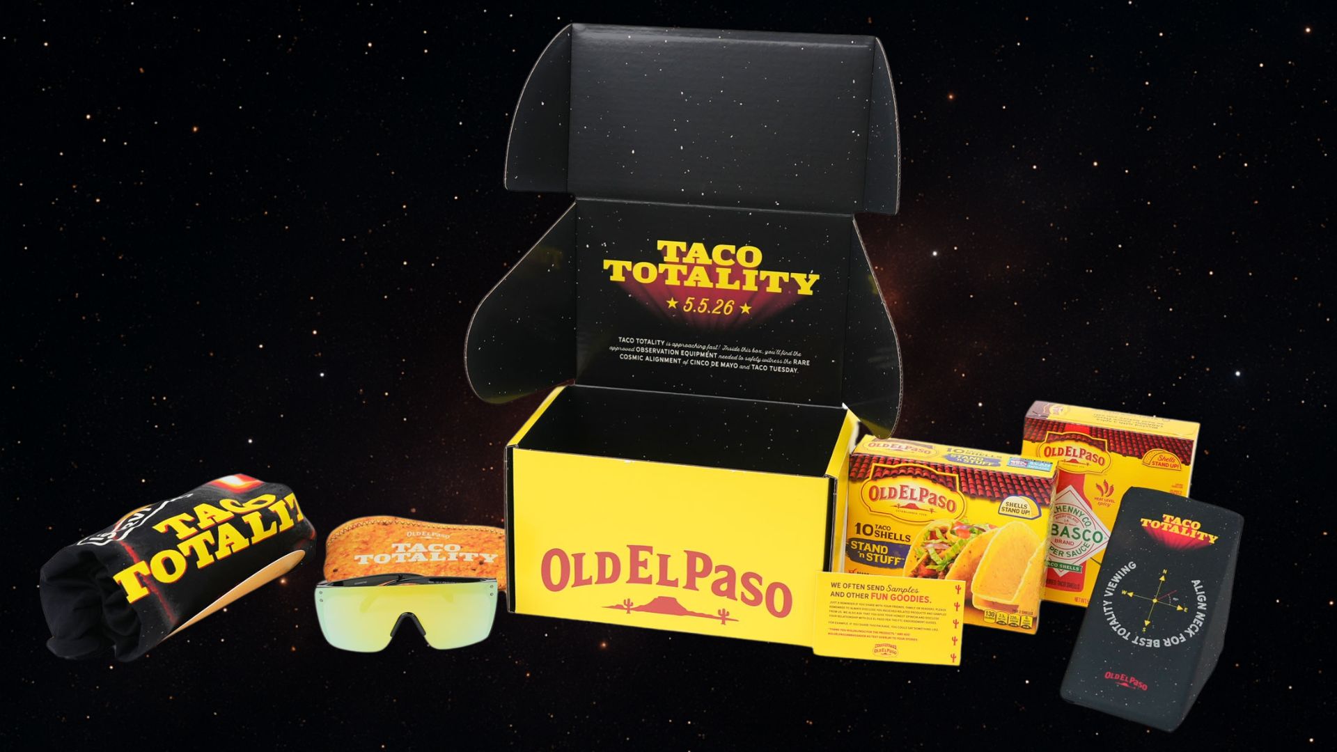 ​An Old El Paso “Taco Totality” gift box is displayed against a starry, space-themed background, open to reveal taco-inspired items including a neck pillow, protective glasses, and Tabasco taco shells. The image highlights the brand’s limited-edition gear and new product launch celebrating the rare alignment of Cinco de Mayo and Taco Tuesday.